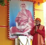 Devotee offering prayers before Swami Sivananda portrait