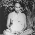 Swami Sivananda meditating peacefully beneath sacred tree