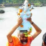 Devotee carrying Lord Ganesha idol with joyful devotion