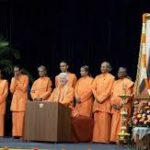 Monks honoring guru portrait during spiritual gathering with devotion and reverence