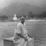 Swami Sivananda seated peacefully beside sacred river in Rishikesh