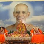 Prayer ceremony honoring revered spiritual guru with devoted disciples and offerings