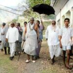 Swami Sivananda walking with devotees under umbrella