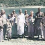 Swami Sivananda with disciples beside a peaceful lake