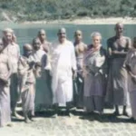 Swami Sivananda with disciples beside a peaceful lake