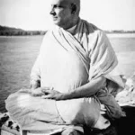 Sri Swami Sivananda meditating peacefully beside a river in serene surroundings