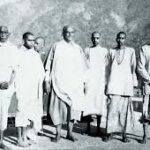 Sri Swami Sivananda with fellow monks and disciples near a peaceful lakeside