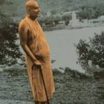 Sri Swami Sivananda standing peacefully in nature near a riverside