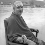 Swami Sivananda seated peacefully beside sacred riverbank meditating