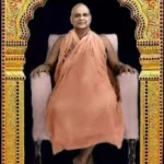 Swami Sivananda sitting in ornate golden frame.