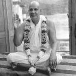 Swami Sivananda seated with raised hand in blessing