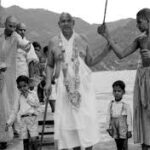 Swami Sivananda walking with devotees under umbrella