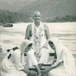 Swami Sivananda with disciples beside peaceful river