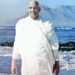 Swami Sivananda standing beside peaceful ocean shore