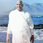 Swami Sivananda standing beside peaceful ocean shore