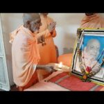 Devotees performing Puja before revered spiritual guru portrait with aarti