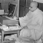 Swami Sivananda writing spiritual teachings at his desk surrounded by sacred books