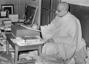 Swami Sivananda writing spiritual teachings at his desk surrounded by sacred books