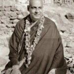 Swami Sivananda seated wearing flower garland