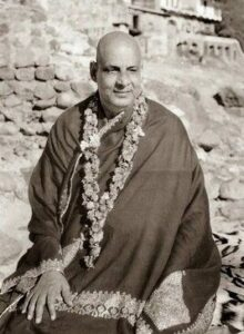 Swami Sivananda seated wearing flower garland