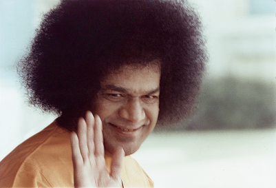 Sathya Sai Baba blessing devotees with a smile.