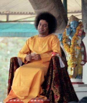 Young Sri Sathya Sai Baba seated peacefully beneath sacred tree